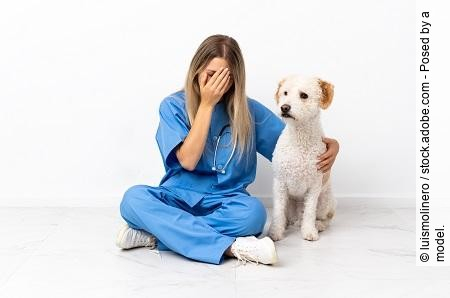 Young veterinarian woman with dog sitting on the floor with tire