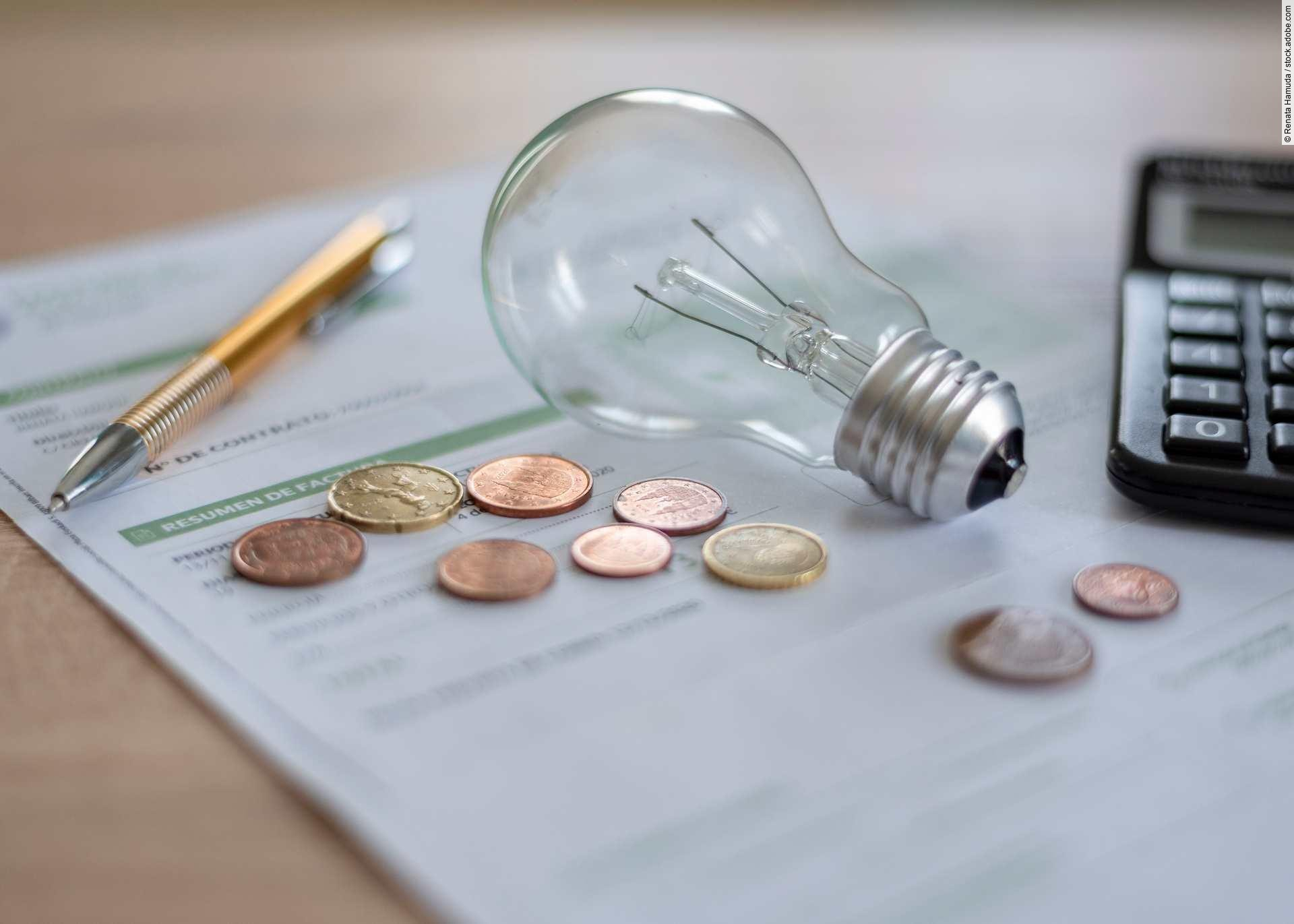 Electricity bill with light bulb, several coins, calculator and 